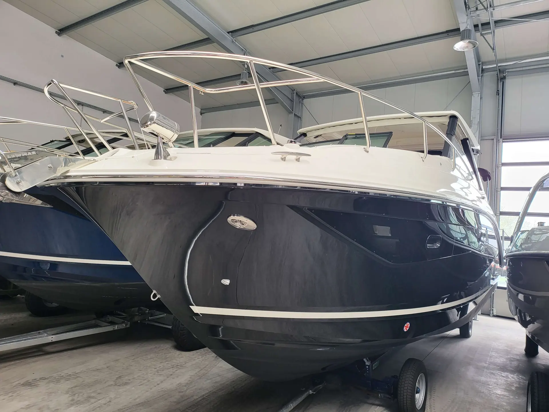 Sea Ray 320 DAE — Vue de face d’un bateau à moteur blanc et bleu dans un hangar.