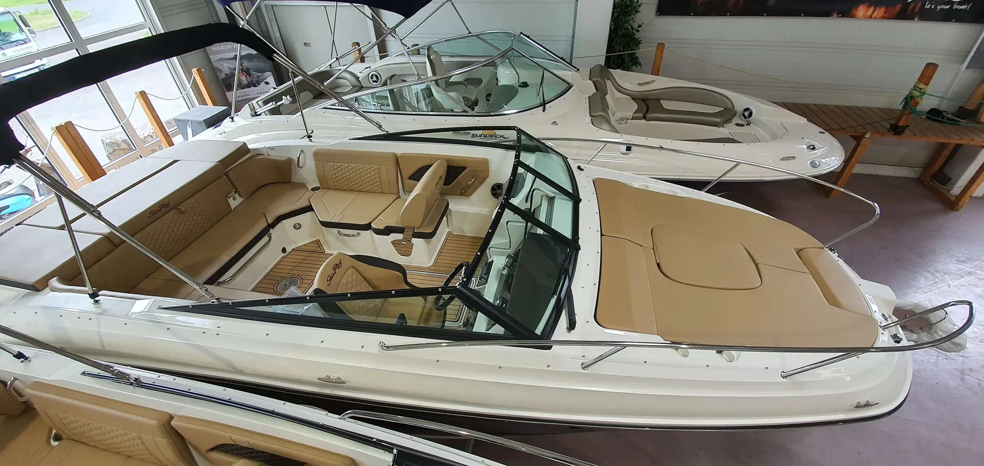 Sea Ray 230 SSE — Vue plongeante du pont avant et du cockpit d’un bateau exposé en intérieur.