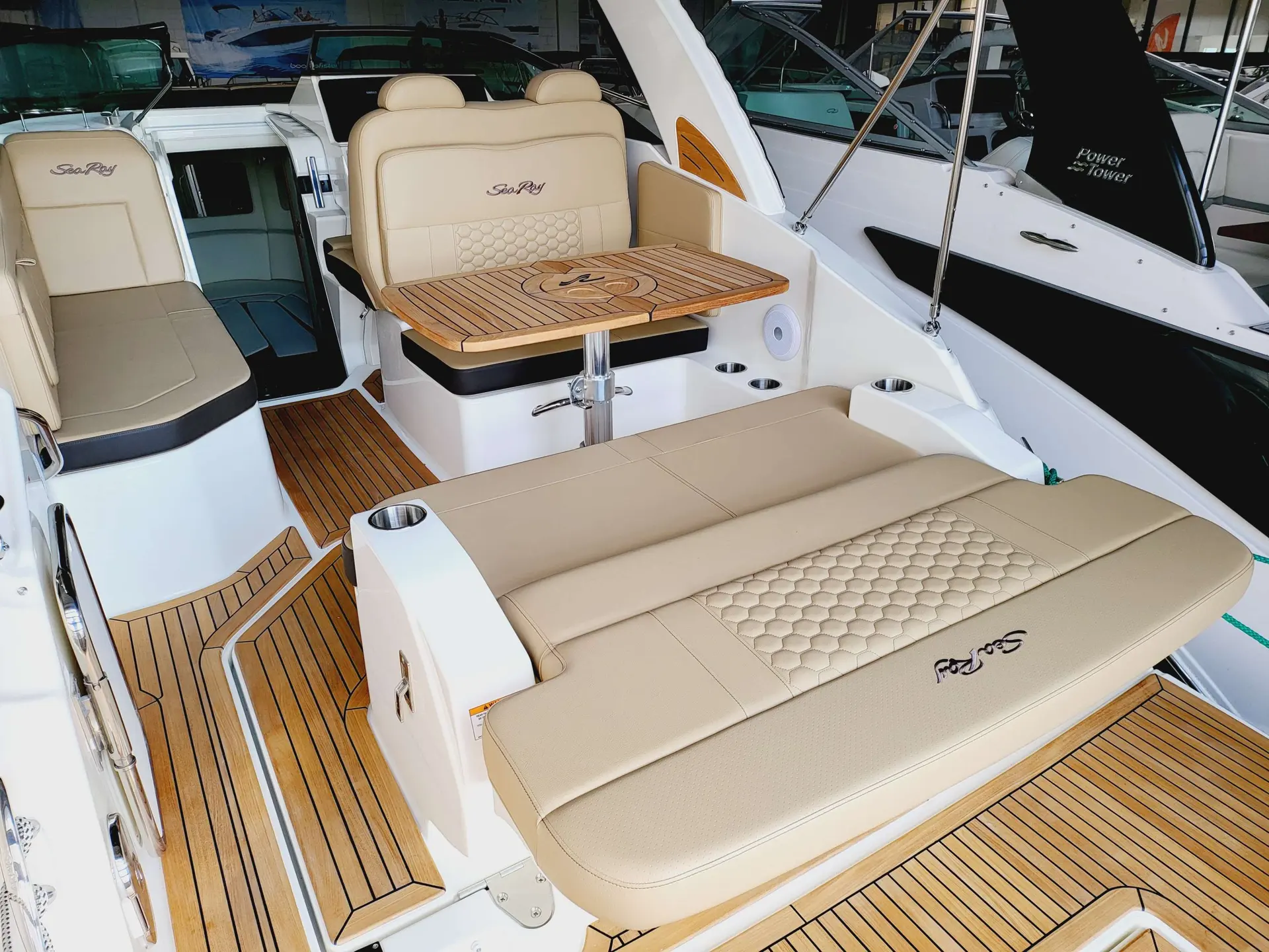 Sea Ray 265 DAE — Cockpit extérieur avec banquettes, table et sellerie claire sur un bateau.