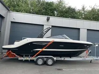 Sea Ray 250 SLXE — Bateau à moteur noir et blanc présenté sur une remorque devant un bâtiment.