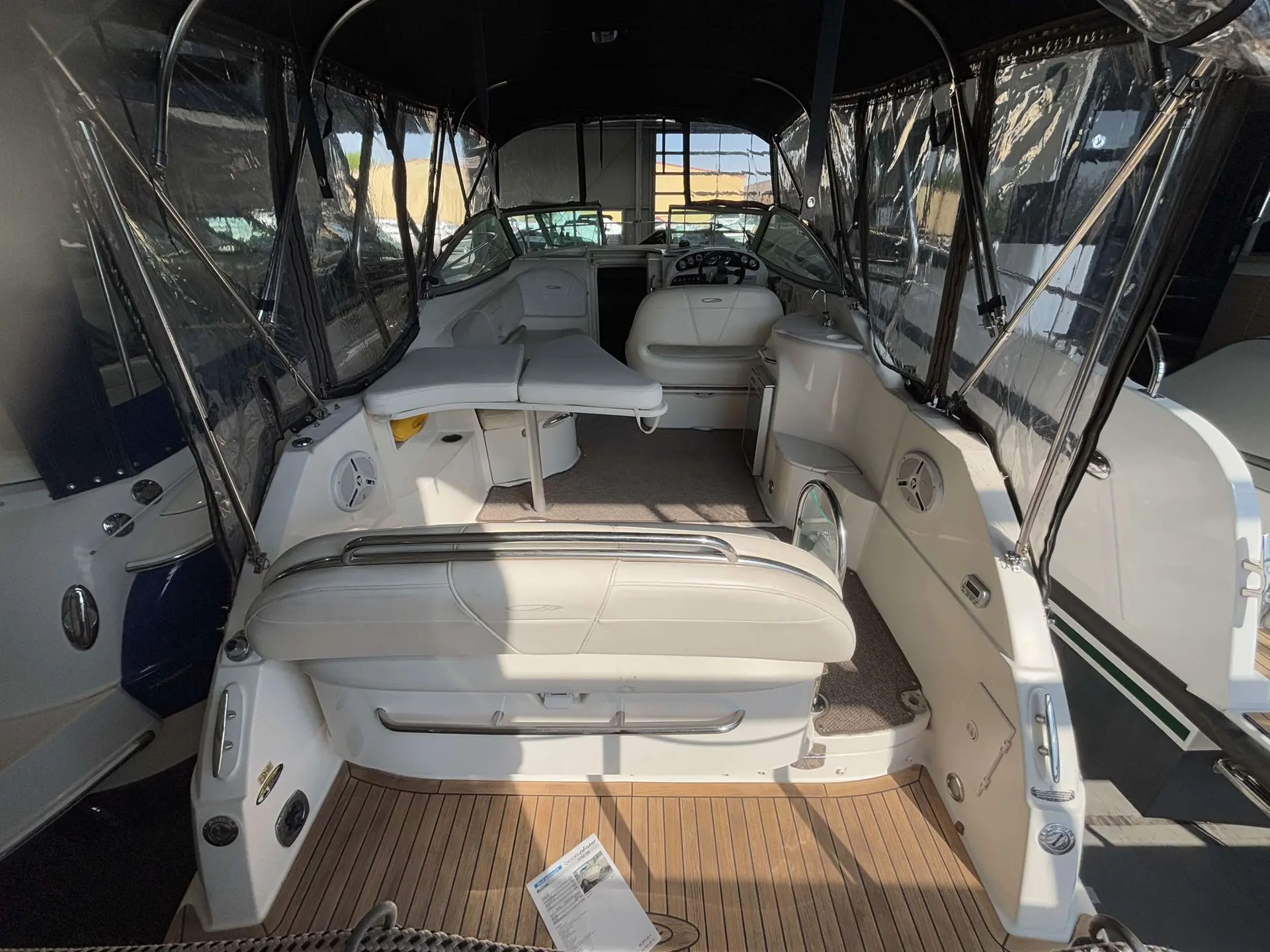 Maxum 2700 — Vue du cockpit couvert d’un bateau, avec sièges, poste de pilotage et pont arrière.