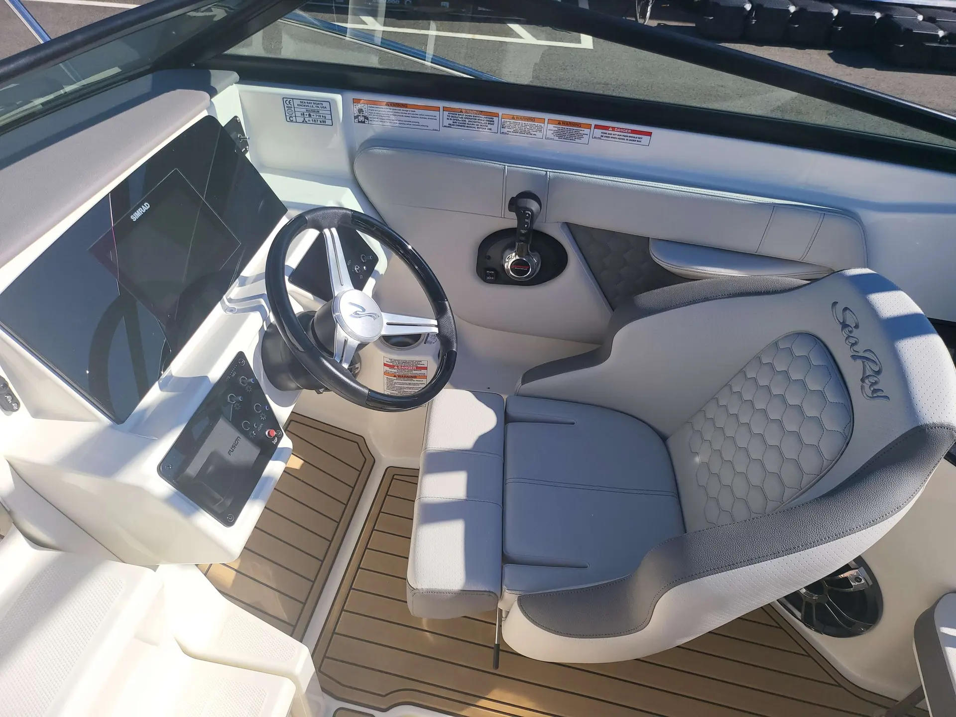 Sea Ray 230 SSOE — Poste de pilotage avec volant, écrans de navigation et siège baquet.