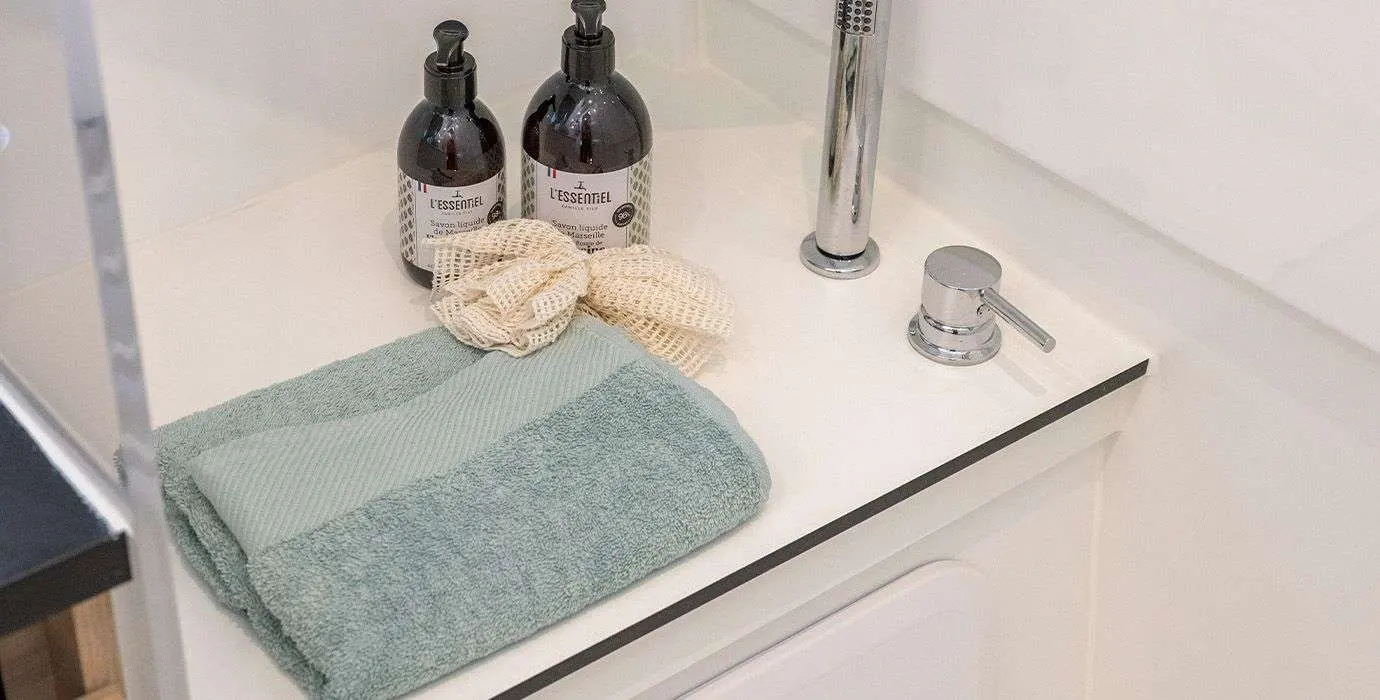 Delphia 10 Sedan — Vue rapprochée d'un lavabo avec robinet, serviettes et flacons de toilette.