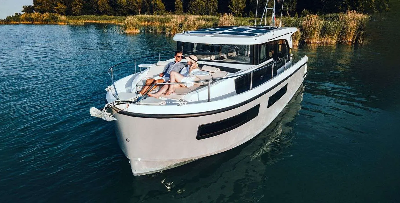 Delphia 11 — Bateau à moteur blanc vu de trois quarts sur un plan d’eau, avec deux personnes à bord.
