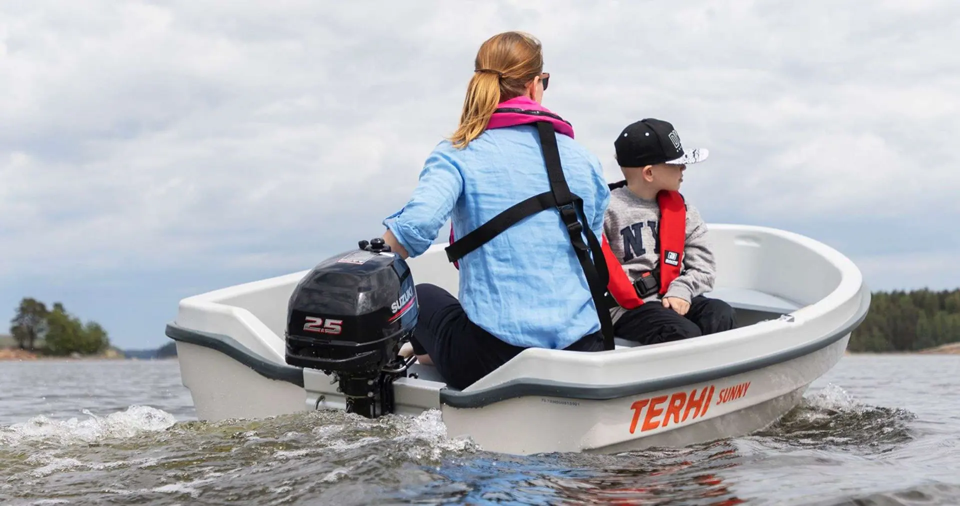 Terhi Sunny — Petit bateau à moteur naviguant sur un lac avec une adulte et un enfant à bord.