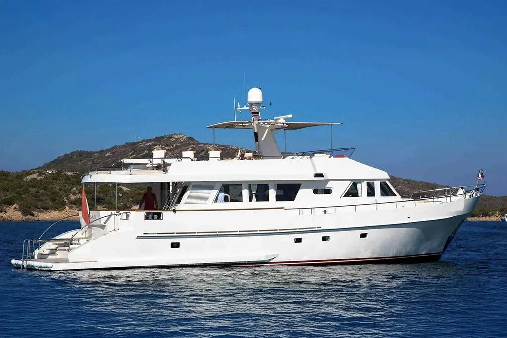 Moonen 70 — Yacht à moteur blanc photographié de profil sur une mer calme, devant une île.