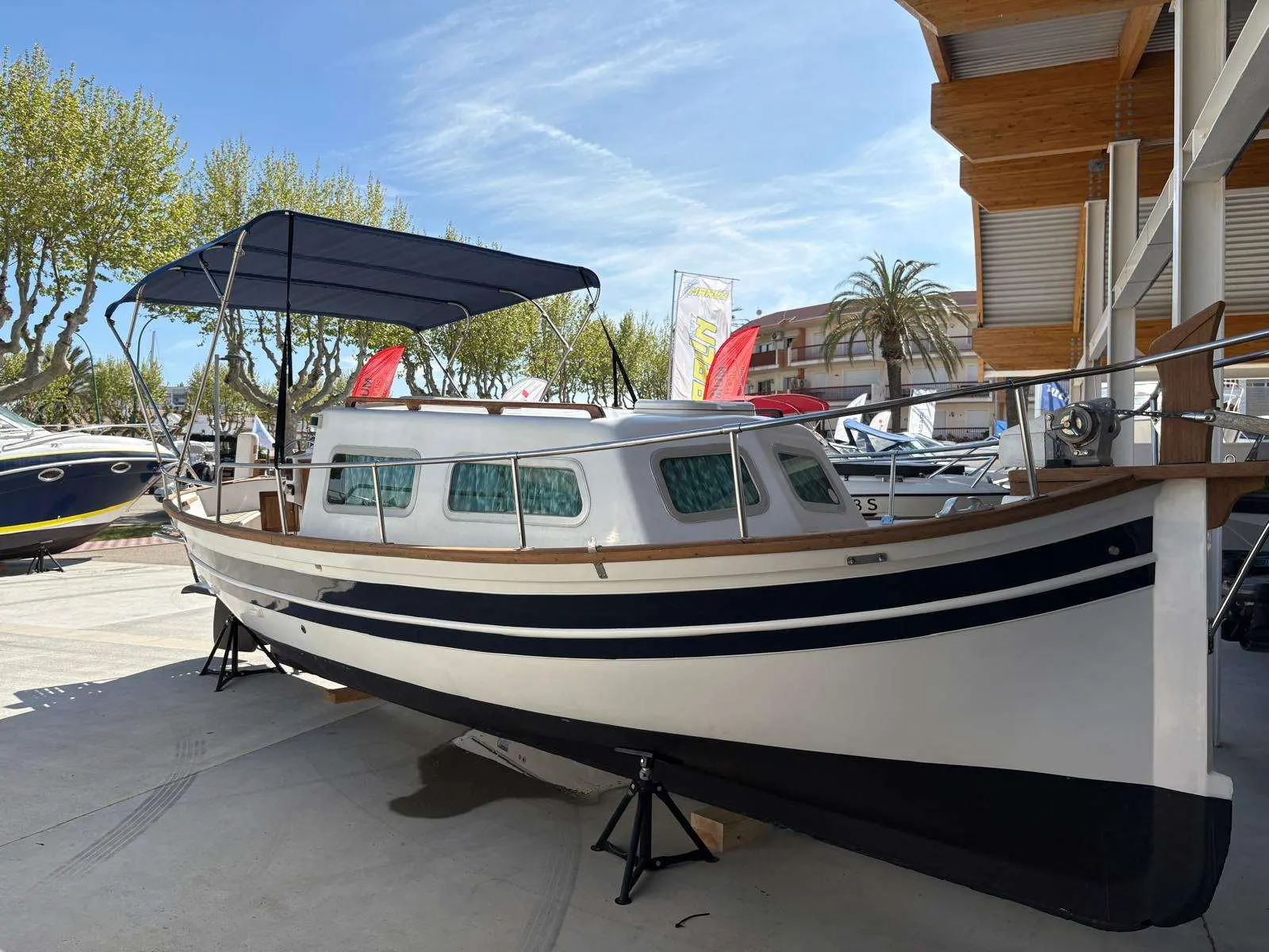 Majoni 36 — Bateau à cabine blanc et bleu présenté à terre sur bers, vu de trois quarts.