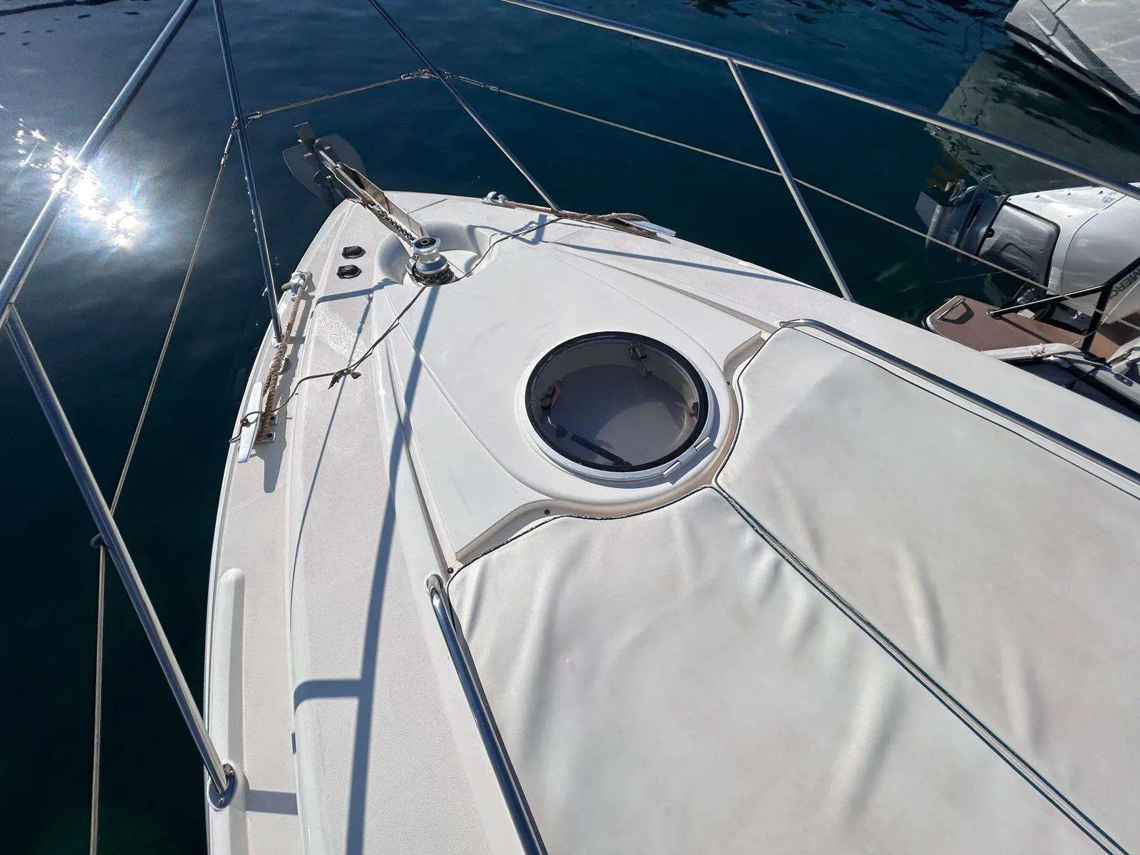 Fairline Targa 37 — Vue rapprochée de la plage avant avec hublot, taud et équipements d'amarrage.