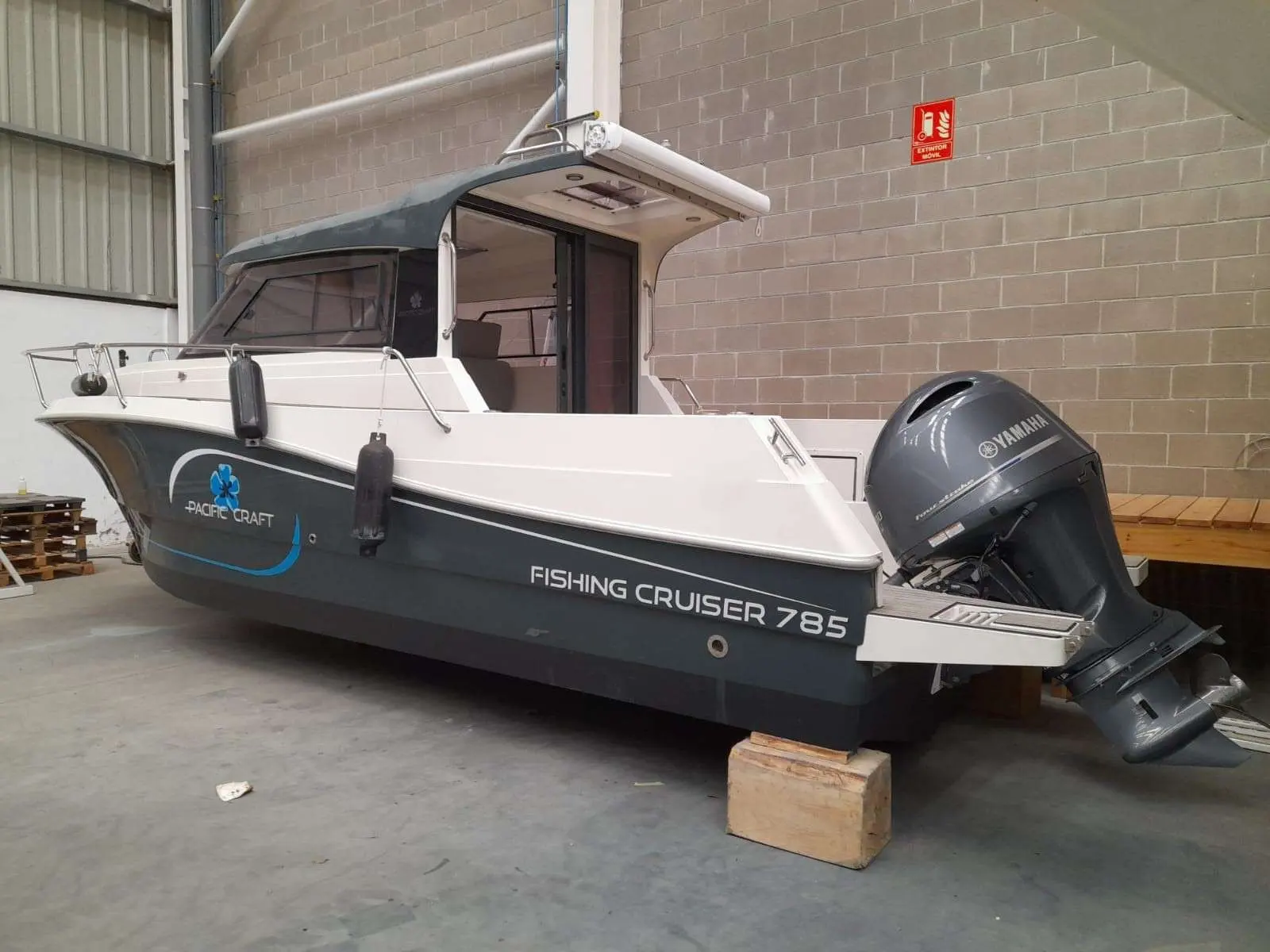 Pacific Craft 785 Fishing Cruiser — Vue trois-quarts d’un bateau à cabine et moteur hors-bord dans un hangar.