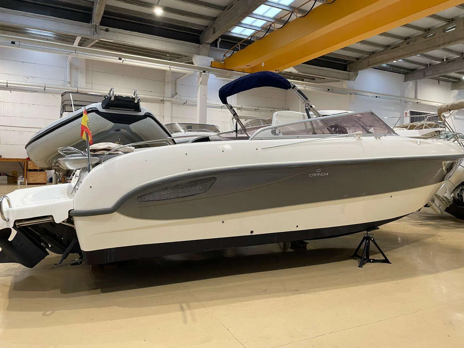 Cranchi CSL 27 — Vue latérale d’un bateau à moteur blanc exposé dans un hangar.