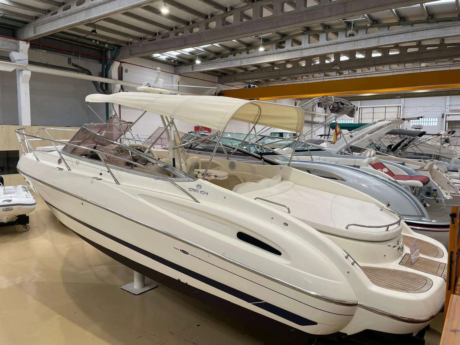 Cranchi CSL 28 — Bateau à moteur blanc photographié sous hangar, avec taud et cockpit visibles.