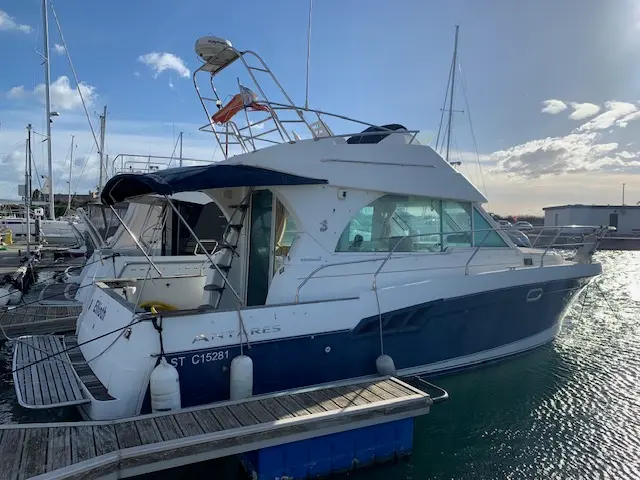 Beneteau Antares 980 — Bateau à moteur blanc et bleu amarré dans un port de plaisance.