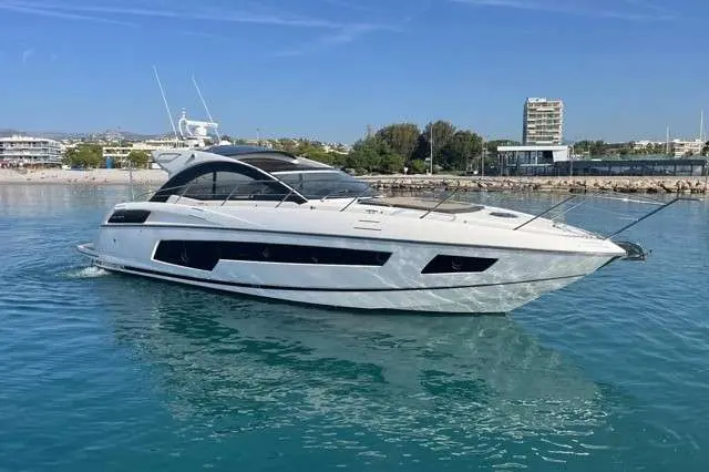 Sunseeker San Remo 485 — Bateau à moteur blanc vu de trois quarts dans un port, sur une eau calme.