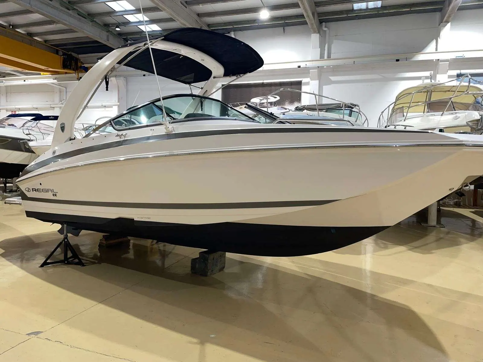 Regal 24 Fastdeck — Vue latérale d’un bateau blanc exposé dans un hangar.