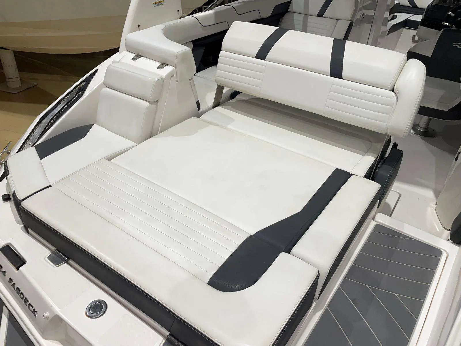 Regal 24 Fastdeck — Vue rapprochée du cockpit avec banquettes et bain de soleil en sellerie blanche.
