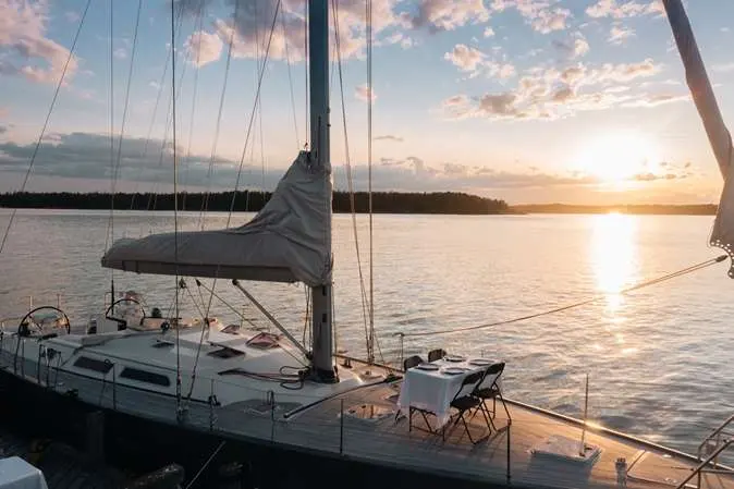 Hanse 531 — Voilier vu de trois quarts au mouillage, au coucher du soleil.
