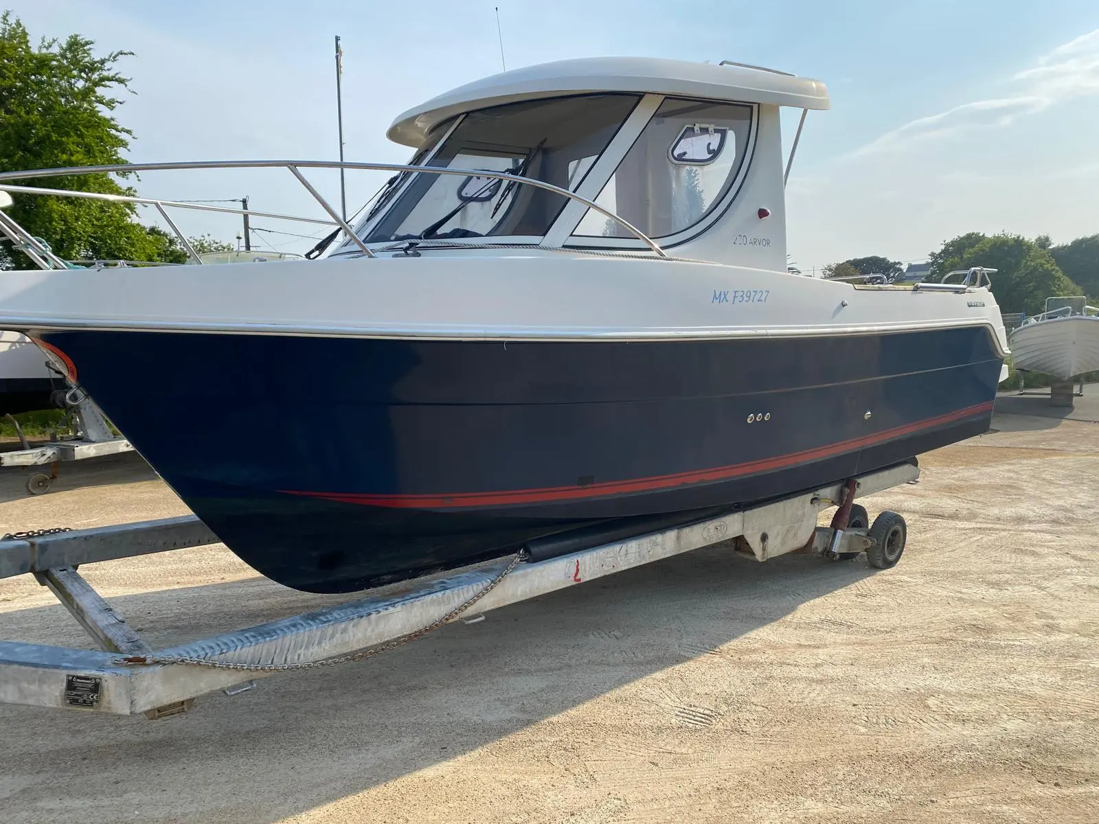 Arvor 230 — Bateau à cabine présenté sur sa remorque, vu de trois quarts avant.