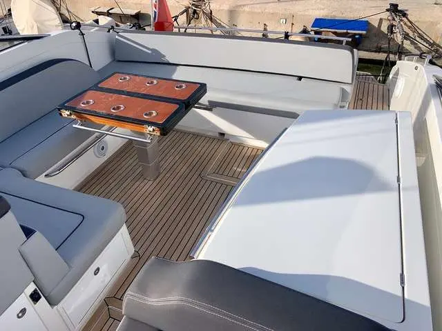 Windy 39 Camira — Vue du cockpit avec banquettes, table centrale et pont en teck.