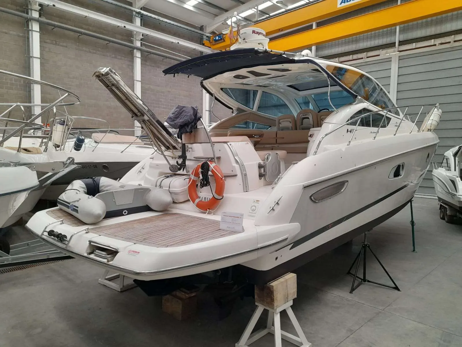 Cranchi Mediterranee 43 — Bateau à moteur blanc photographié de trois quarts arrière dans un hangar.