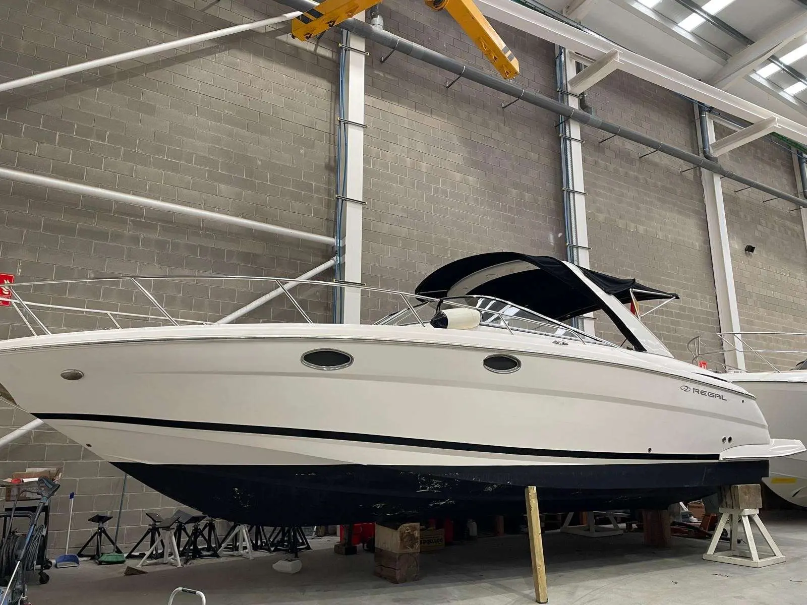 Regal 3550 — Vue latérale d’un bateau blanc exposé sur bers dans un hangar.