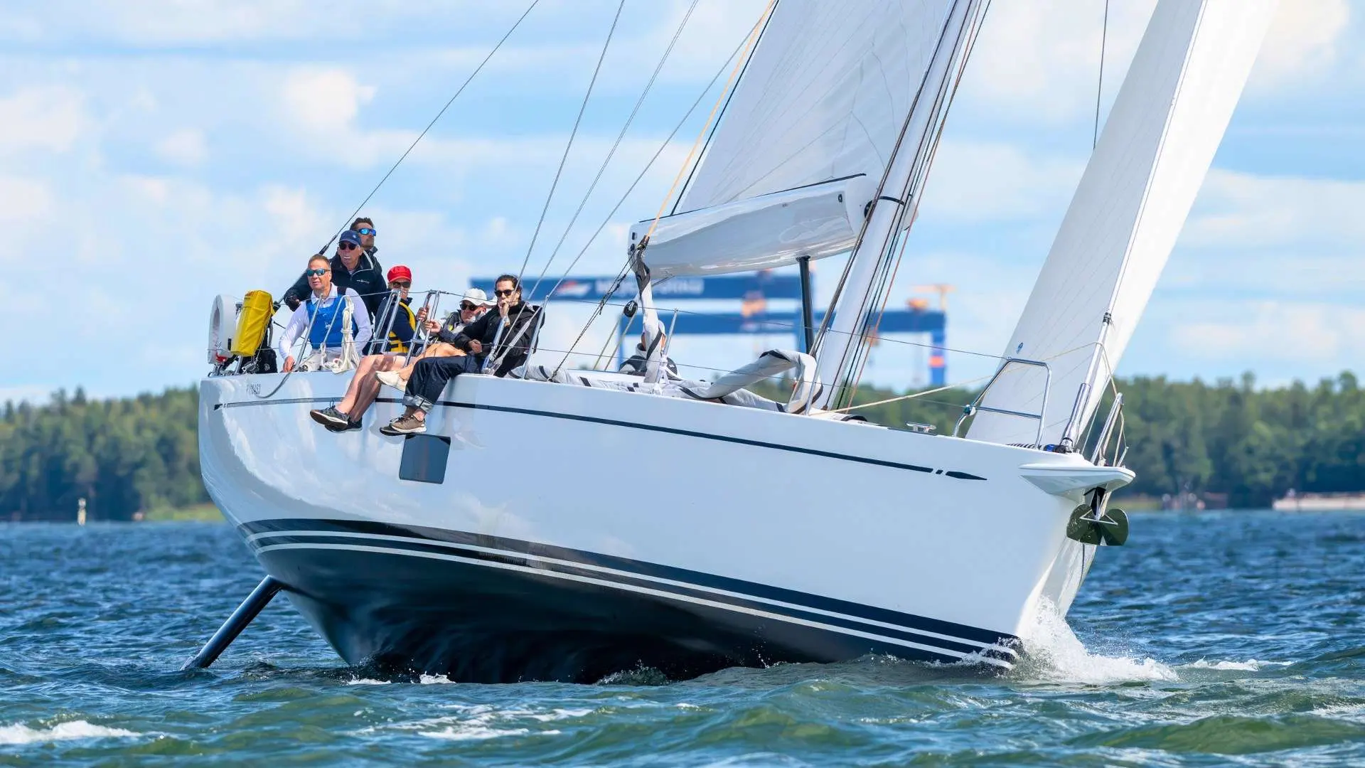 Nautor Swan Swan 55 — Voilier blanc naviguant à la voile sur un plan d’eau, avec plusieurs personnes à bord.