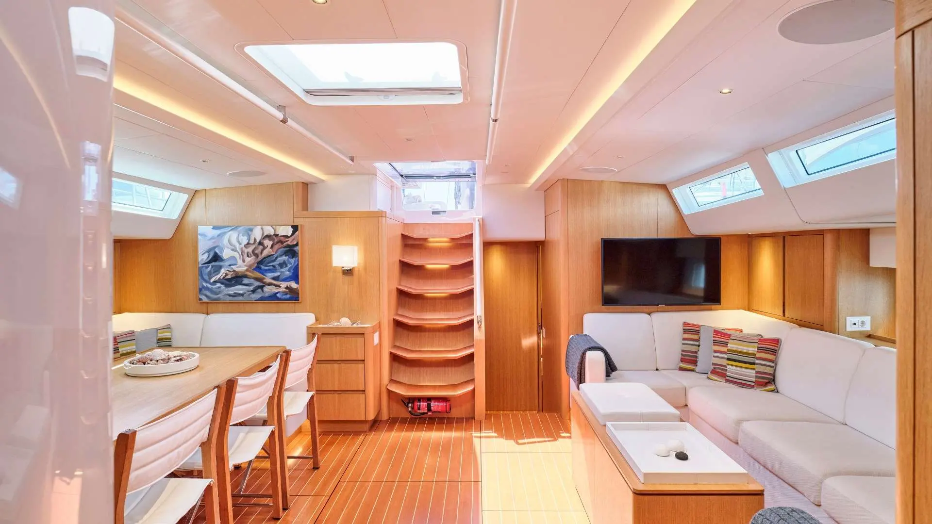 Nautor Swan Swan 78 — Vue du carré avec salon, table à manger, escalier et téléviseur.