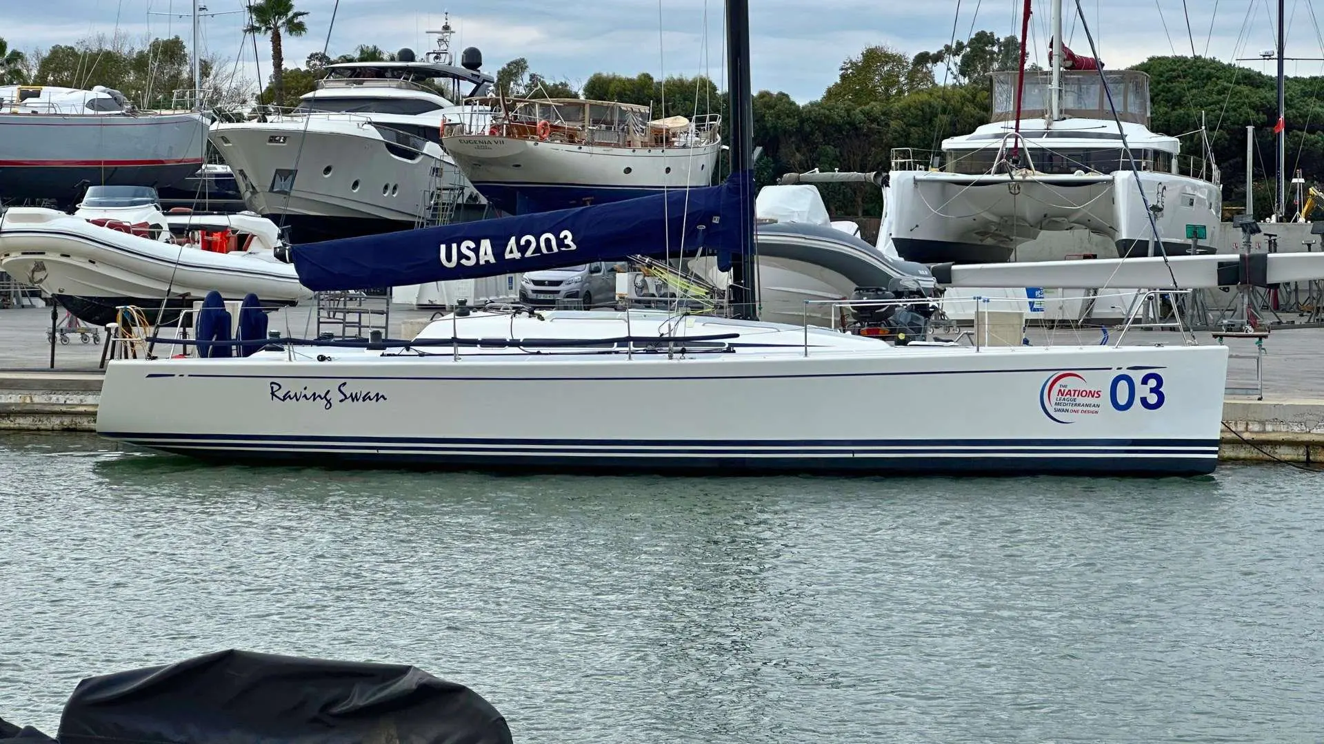 Nautor Swan Swan 42 — Voilier blanc amarré dans un port, vu de profil, avec l’inscription « Racing Swan ».