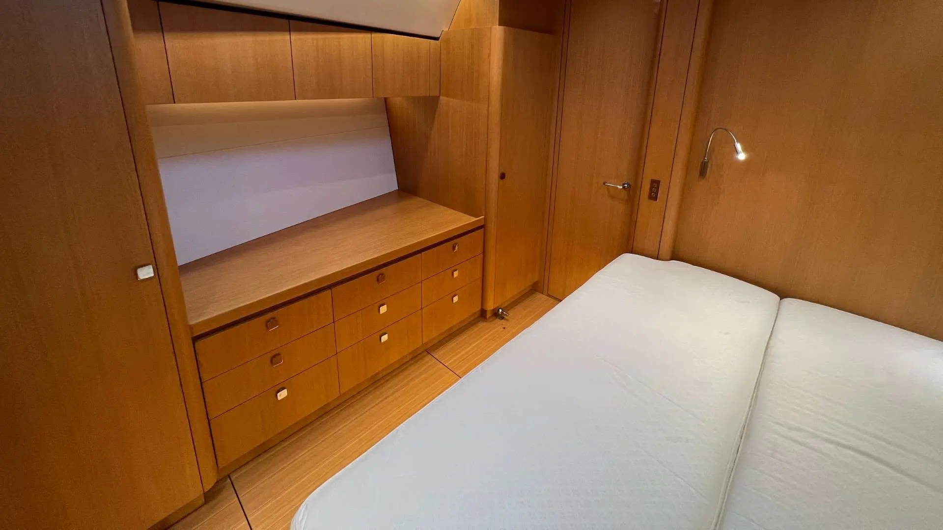 Nautor Swan Swan 60 — Cabine en bois avec couchette double, rangements et éclairage mural.