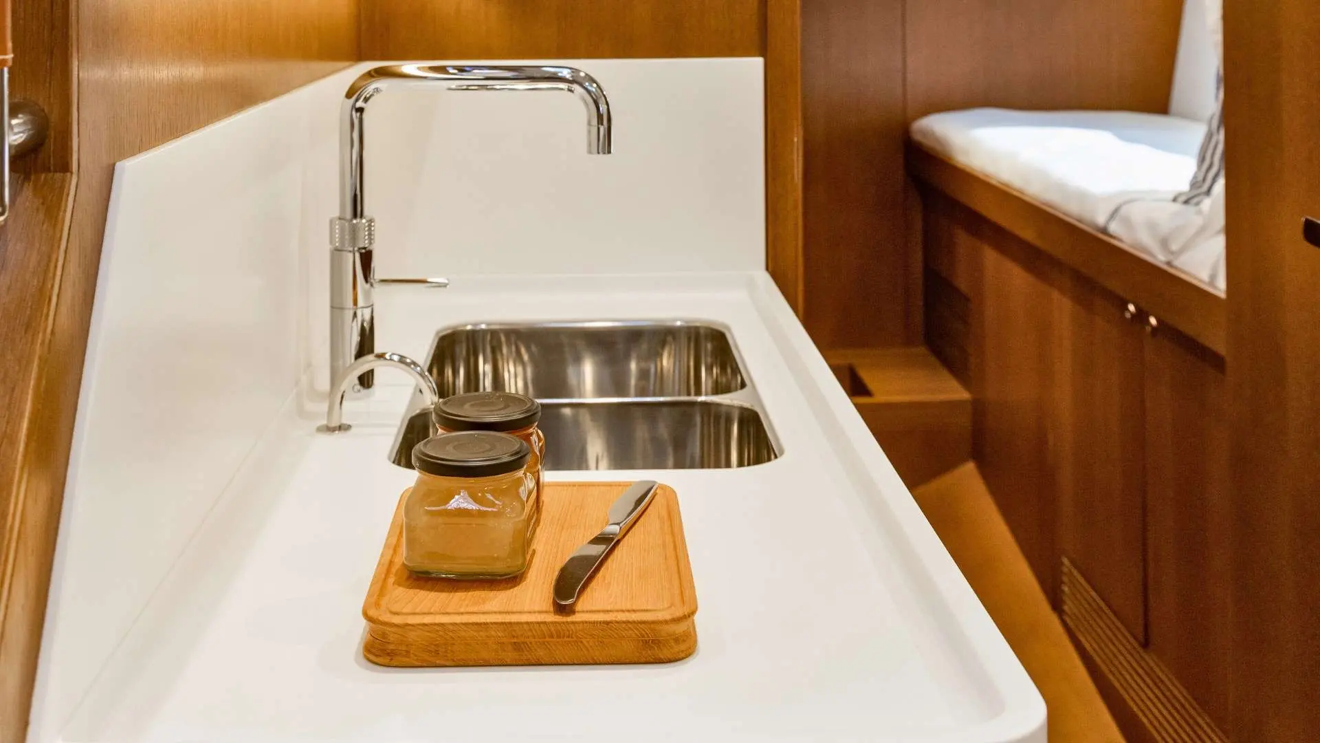 Nautor Swan Swan 55 — Cuisine à bord avec évier double, robinet chromé et couchette en arrière-plan.