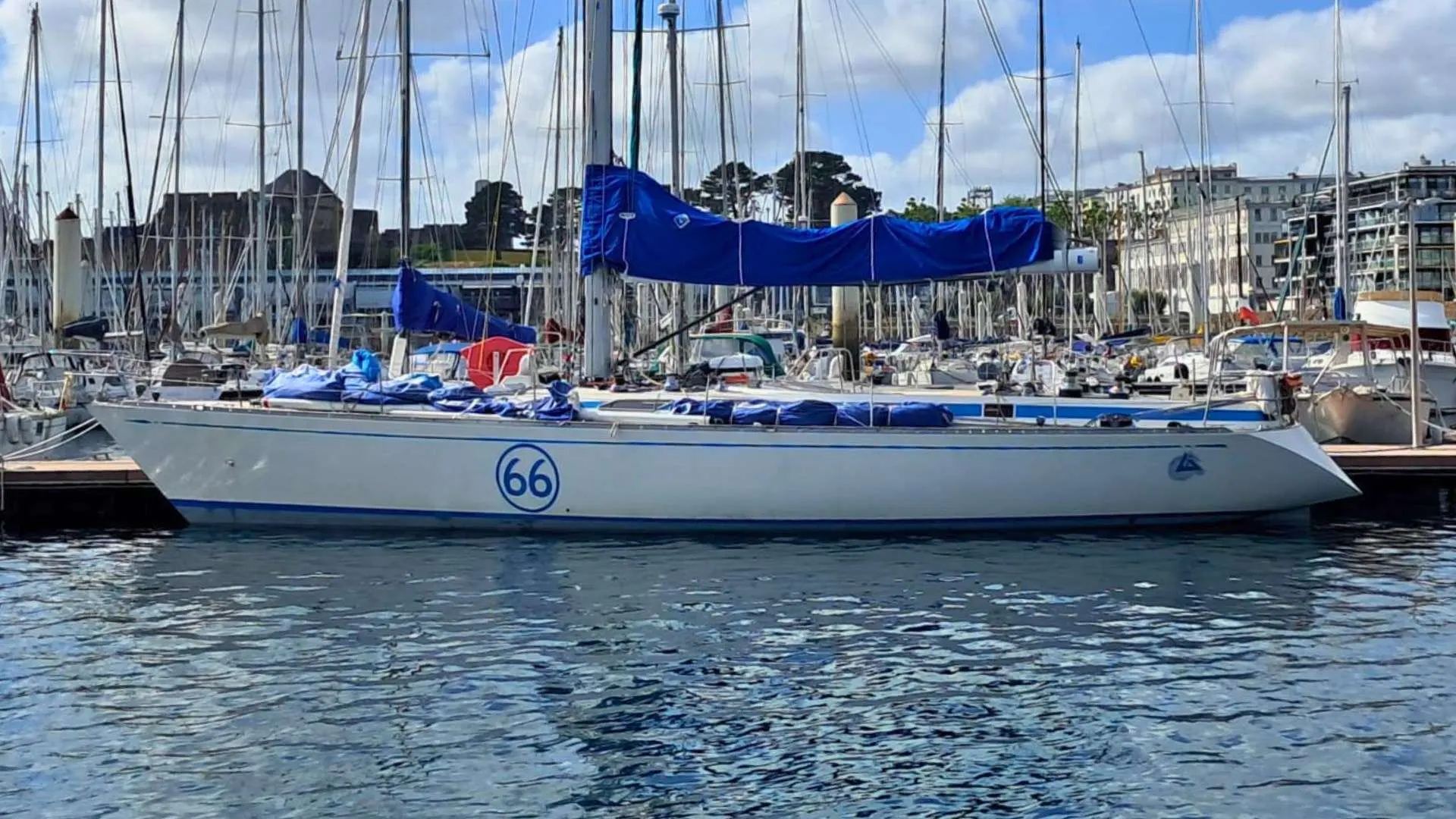 Nautor Swan Swan 53 — Voilier blanc vu de profil dans un port, avec sa grand-voile couverte.