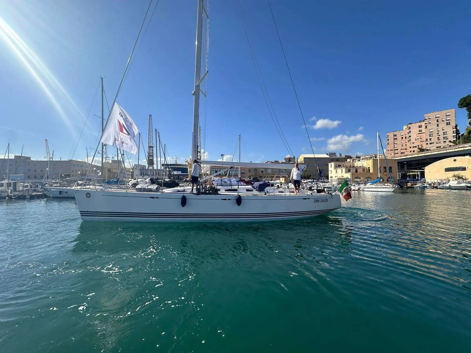 X-Yachts X-50 — Voilier blanc vu de profil dans un port, avec deux personnes à bord.