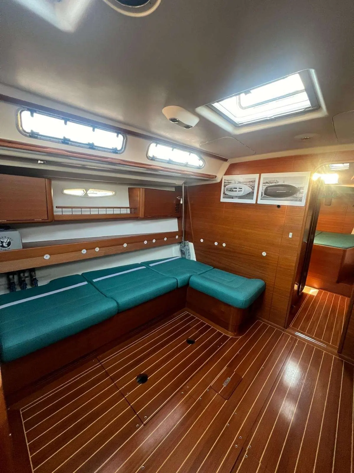 X-Yachts X-50 — Salon intérieur avec banquettes turquoise, boiseries et plancher en teck.