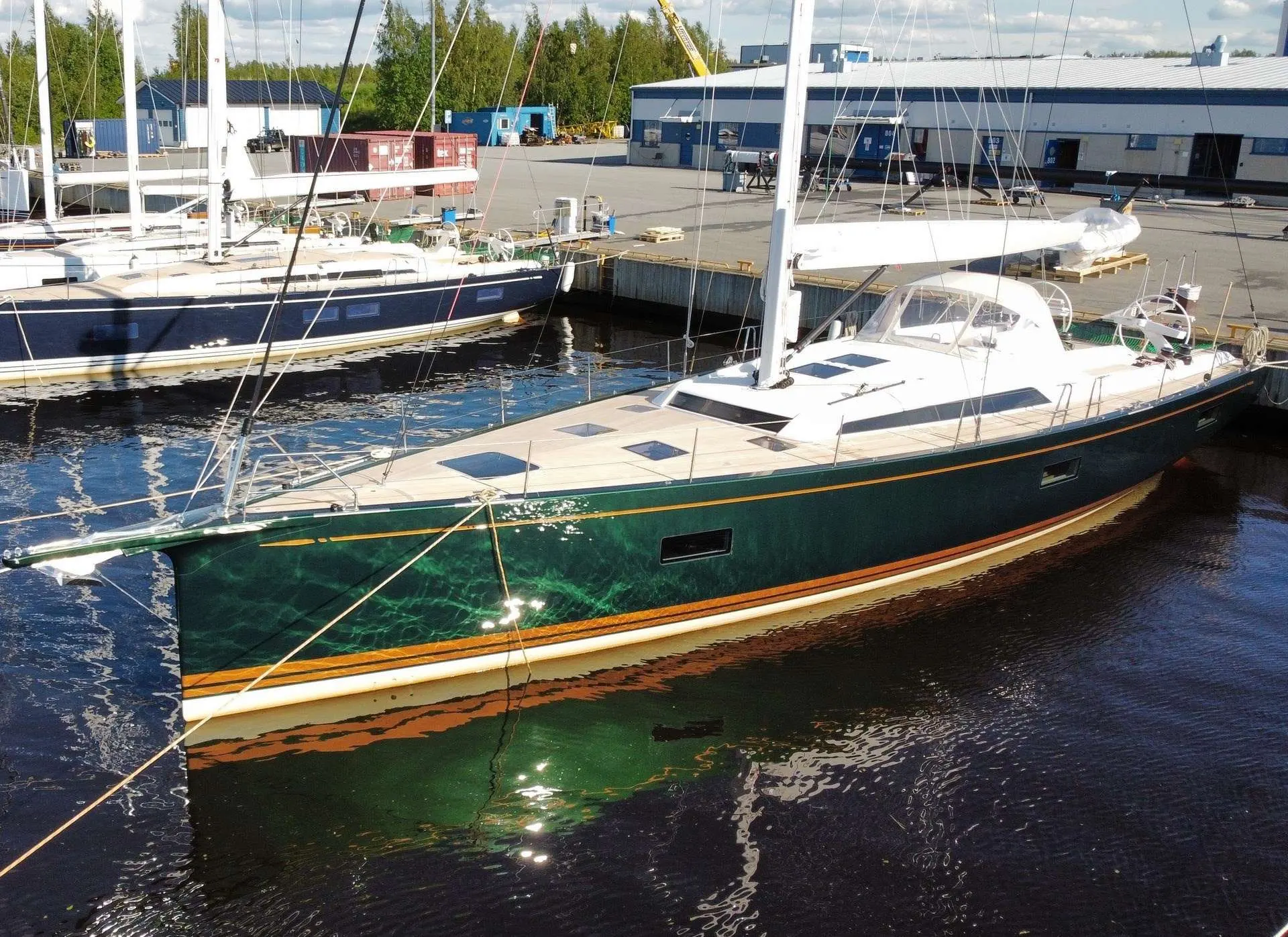 Nautor Swan Swan 65 — Voilier vert amarré dans une zone portuaire, vu de trois quarts.