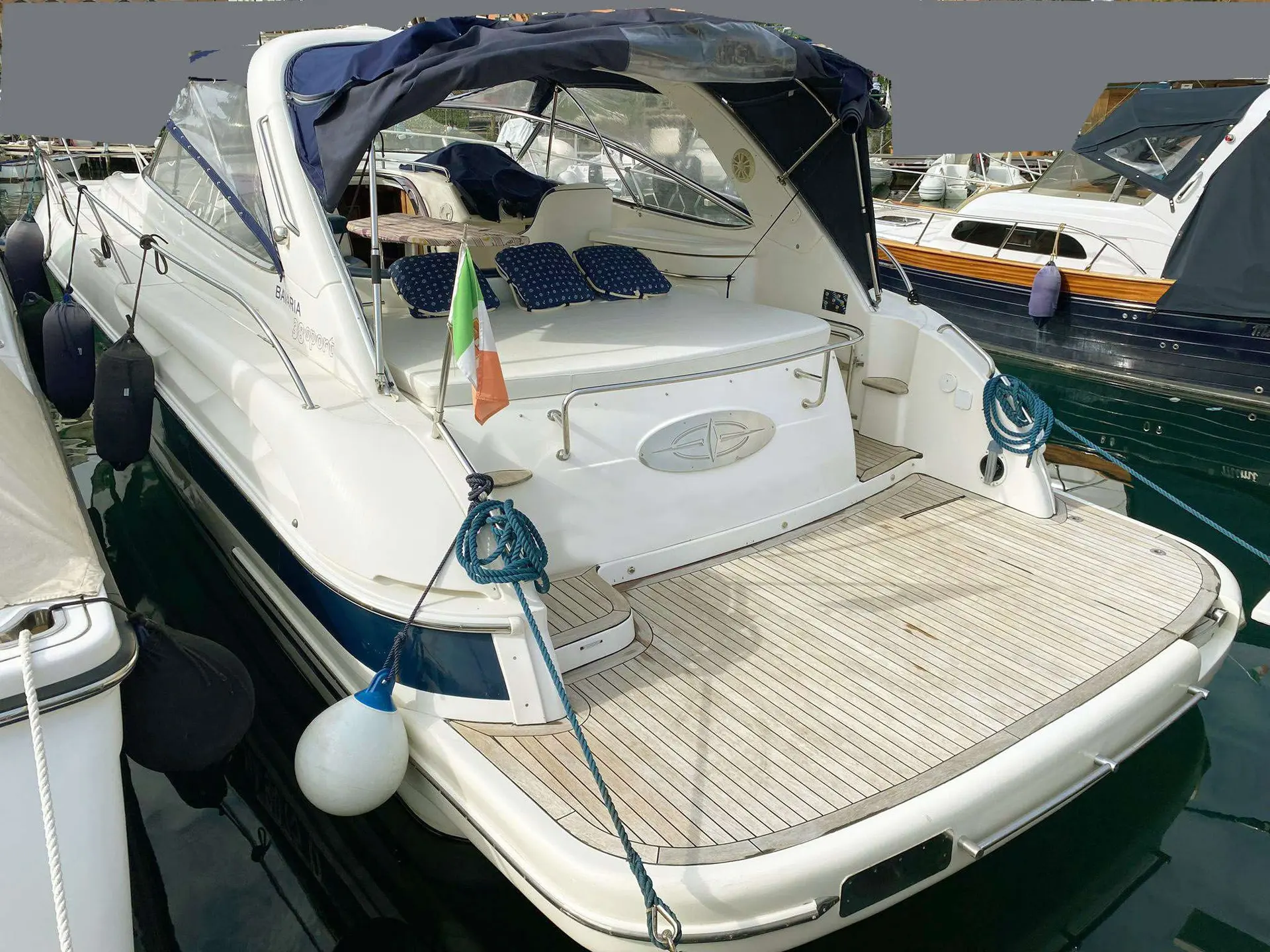 Bavaria Sport 38 — Vue arrière trois-quarts d’un bateau à moteur amarré, avec cockpit et taud.