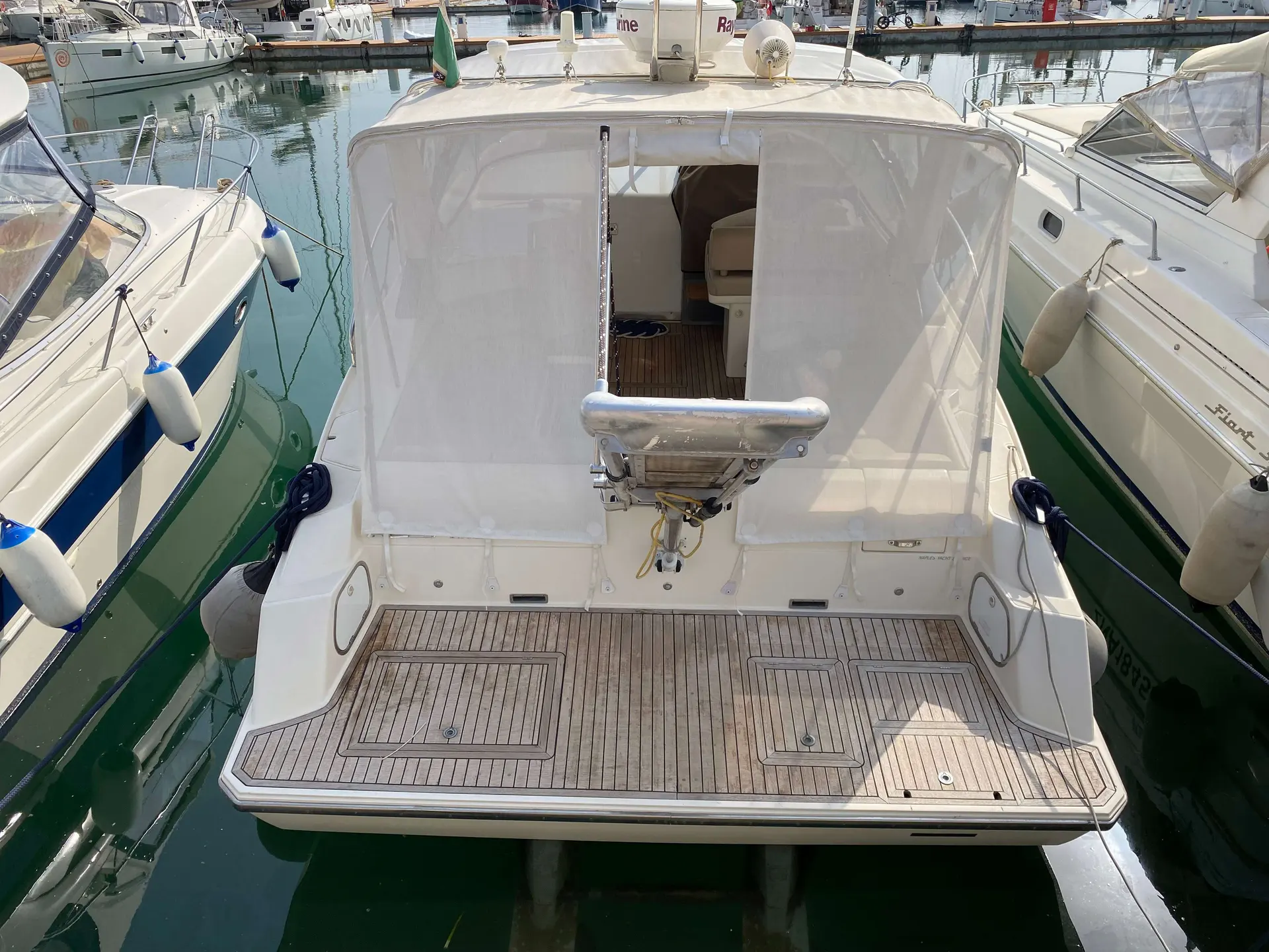Fiart Mare Fiart 34 Genius — Vue arrière d’un bateau amarré, avec cockpit en teck et taud de protection.