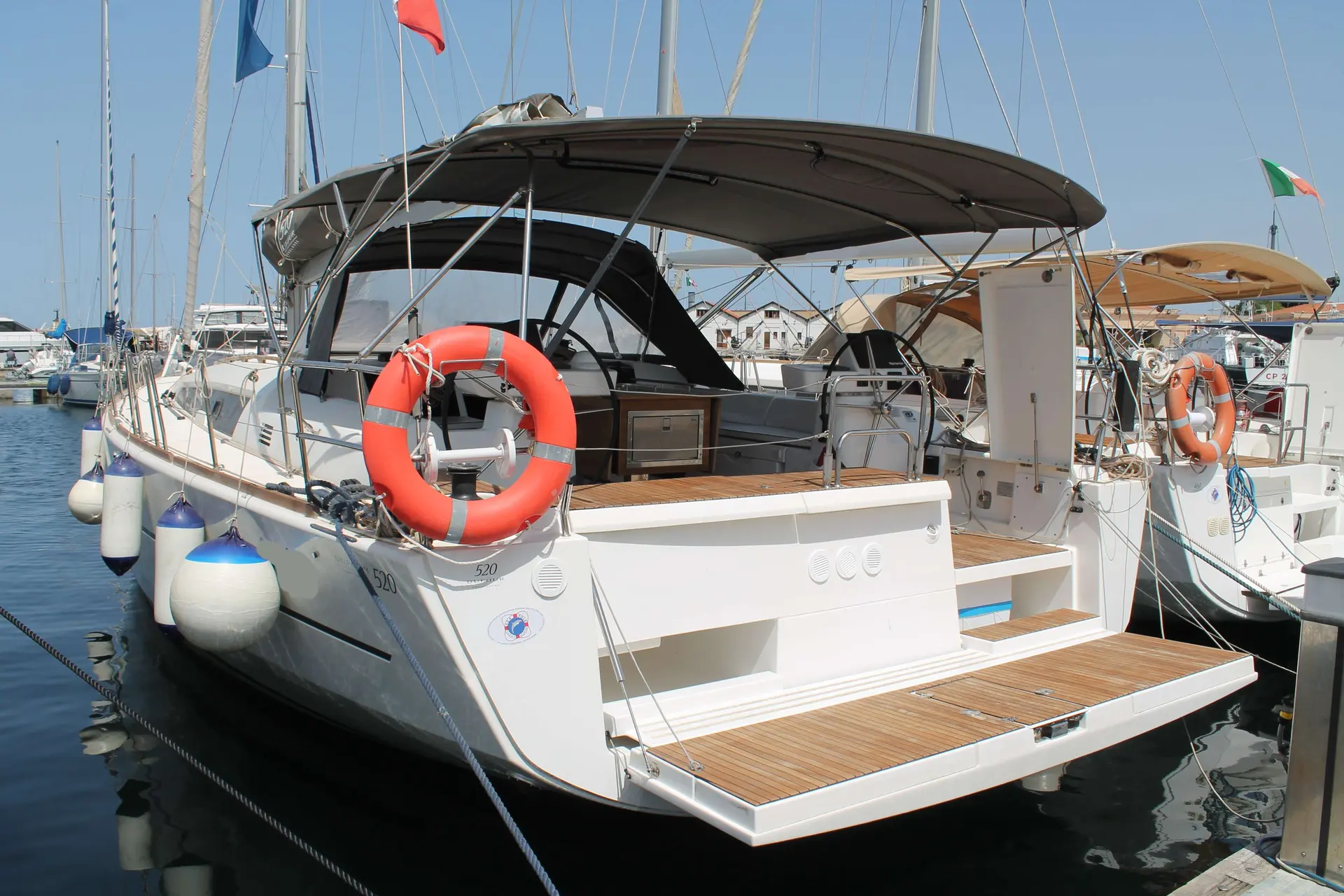 Dufour 520 Grand Large — Voilier amarré vu de trois quarts arrière, avec cockpit et plateforme de baignade.