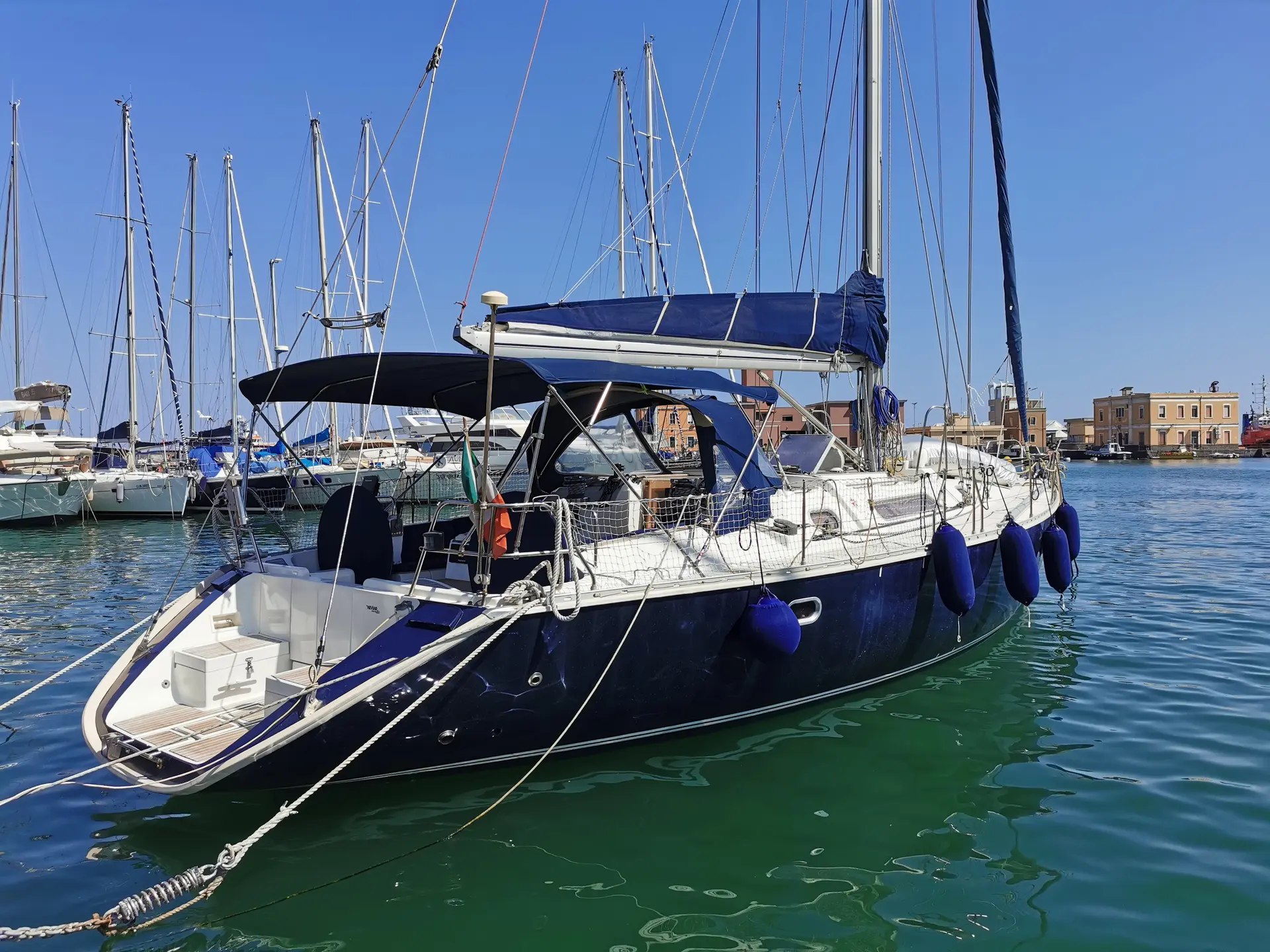 Jeanneau Sun Odyssey 51 — Voilier amarré vu de trois quarts dans une marina, avec bimini et pare-battages.