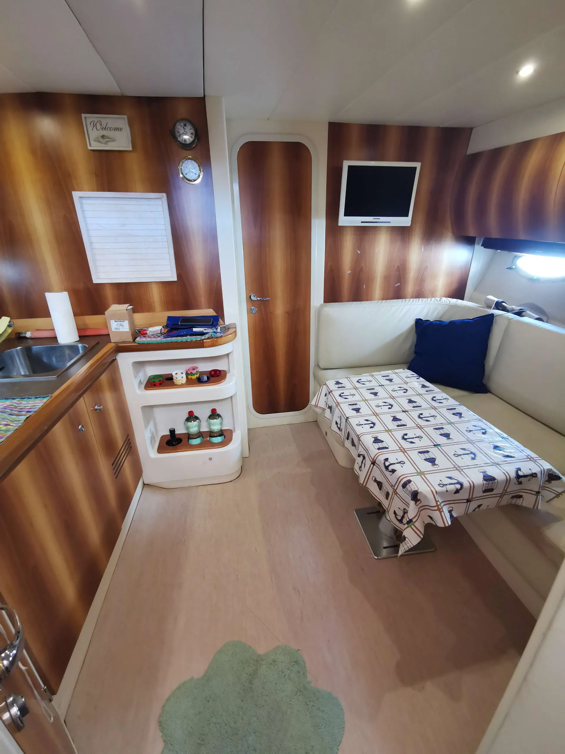 Ilver 39 Mirable — Vue intérieure d'un espace repas avec cuisine, banquette et télévision.