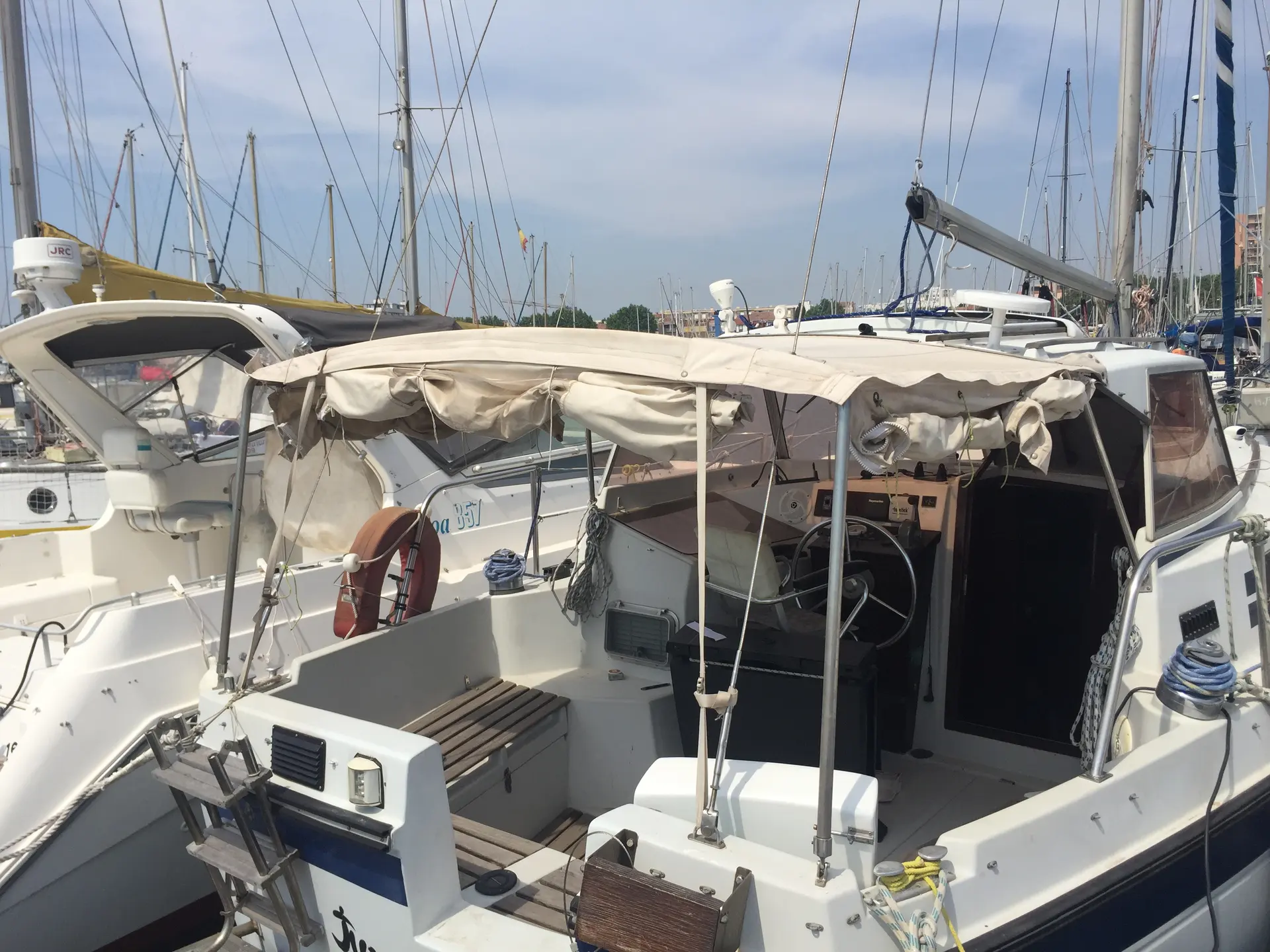 Kirie 33 — Vue du cockpit d’un voilier amarré, avec capote, barre et équipements de pont.