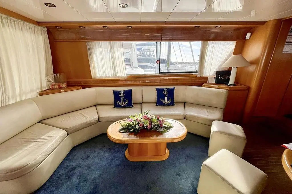 San Lorenzo 70 — Salon intérieur avec canapé en U, table basse, fauteuils et larges fenêtres.