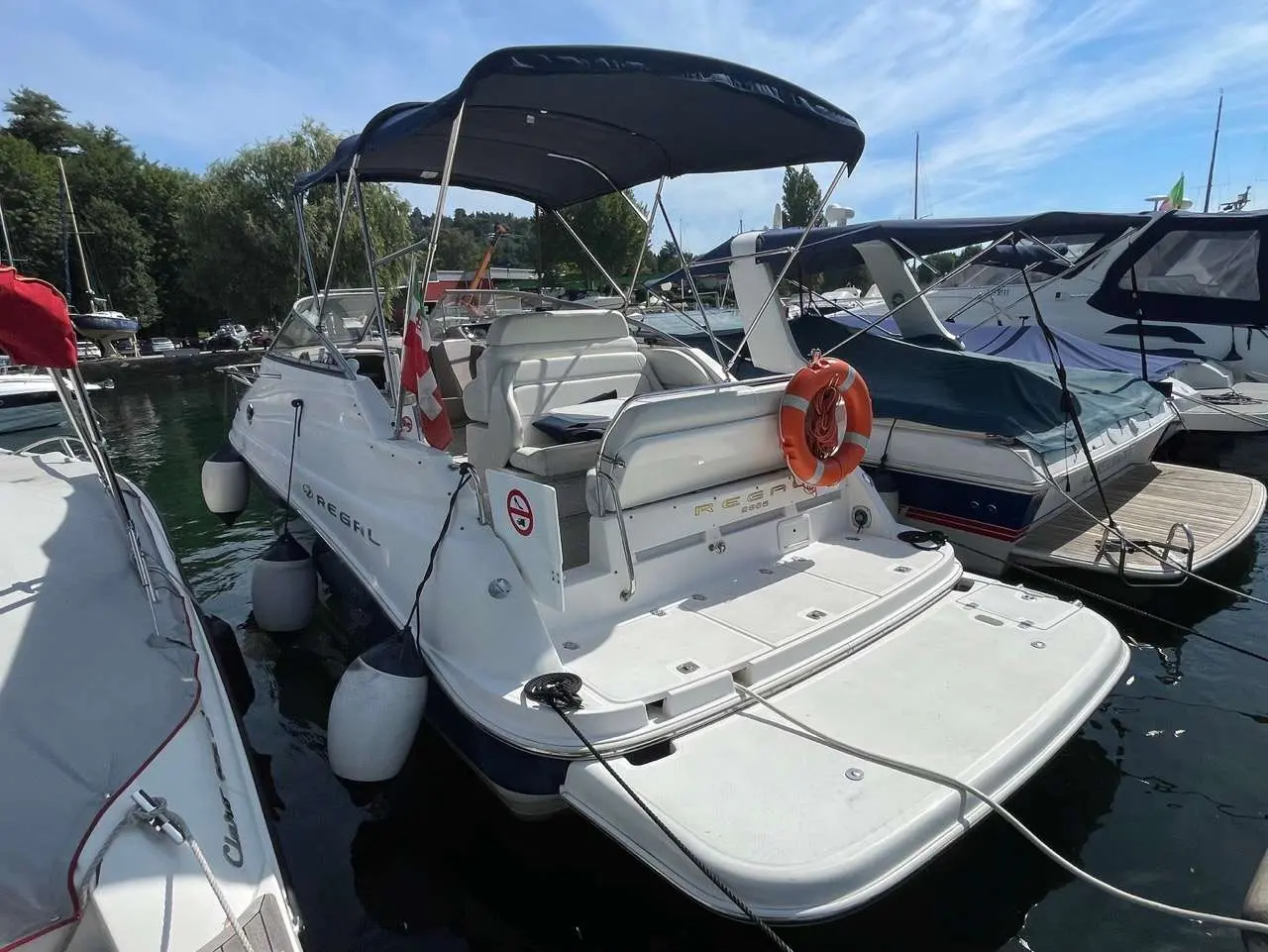 Regal Commodore 2665 — Bateau blanc amarré vu de trois quarts arrière, avec taud et plateforme de baignade.