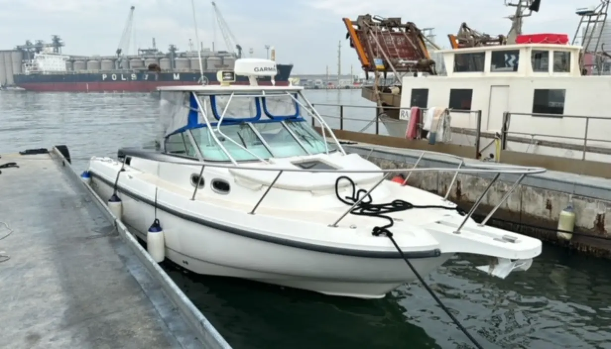 Boston Whaler 285 Conquest — Bateau blanc amarré dans un port, photographié de trois quarts avant.