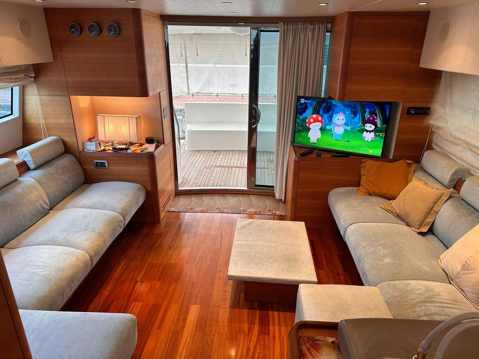 Aicon 64 Fly — Salon intérieur avec banquettes, table basse, télévision et accès au cockpit.