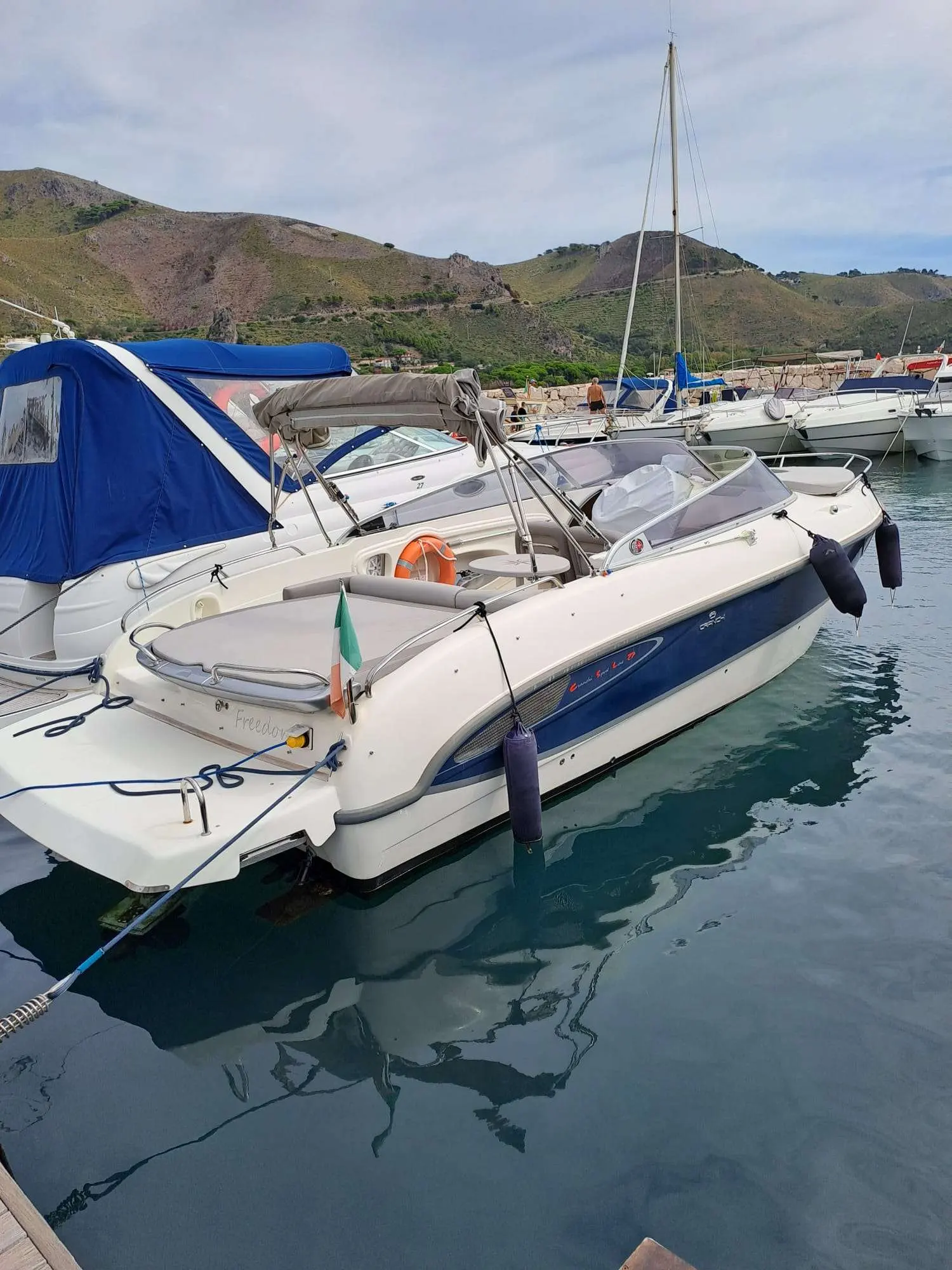 Cranchi CSL 27 — Bateau à moteur blanc et bleu amarré dans un port, entouré d'autres embarcations.