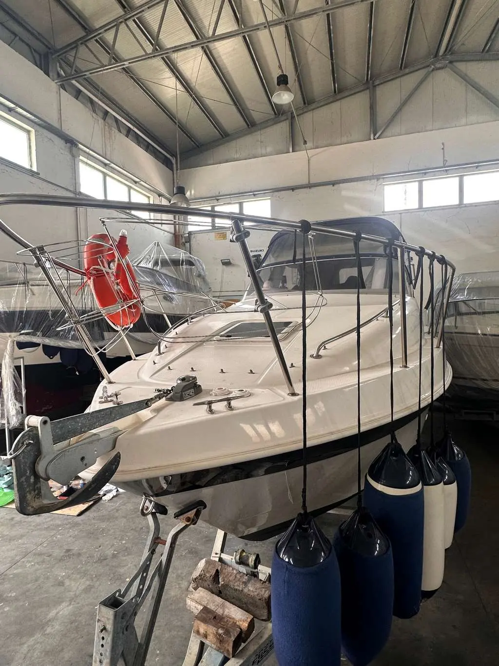 Saver Riviera 24 — Bateau à moteur blanc photographié sur remorque dans un hangar.