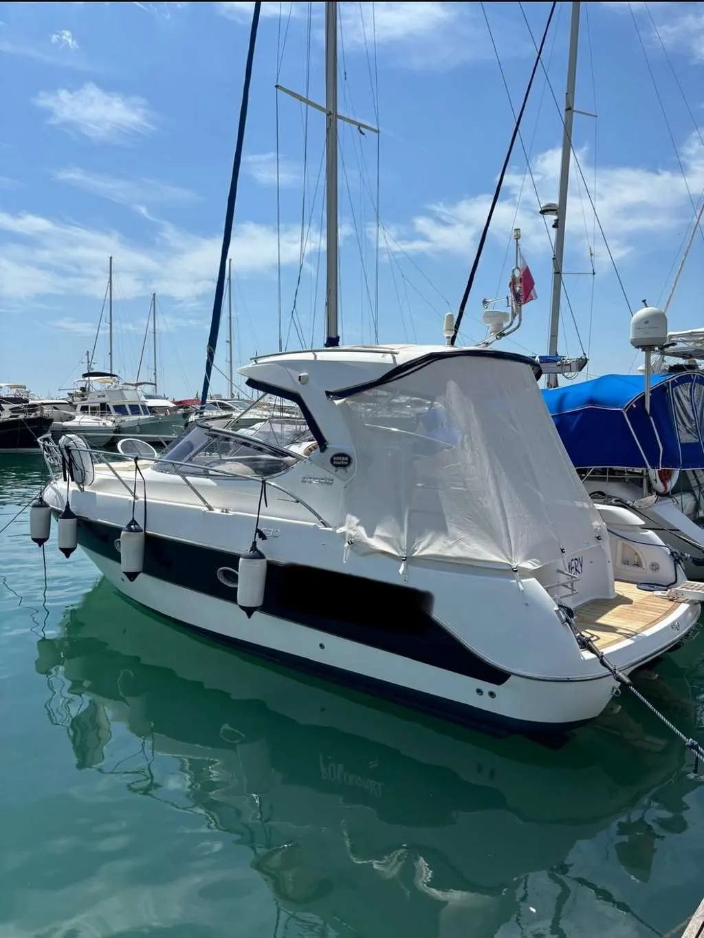 Sessa Marine C30 Hard-Top — Bateau à moteur blanc amarré dans un port, vu de trois quarts arrière.