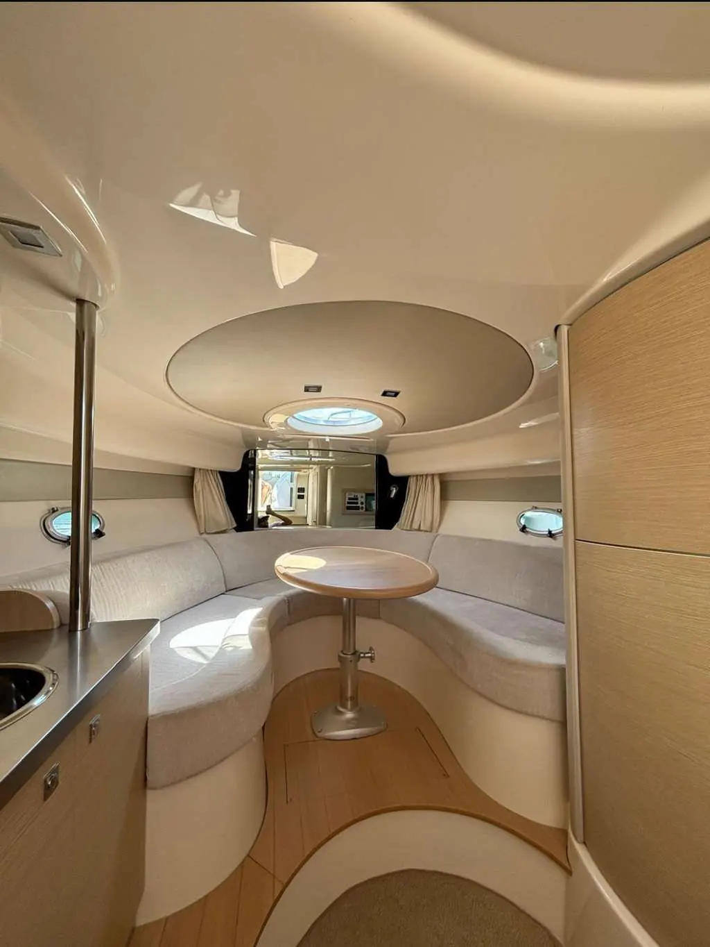 Sessa Marine C30 Hard-Top — Vue intérieure du carré avec banquette en U, table et hublots.