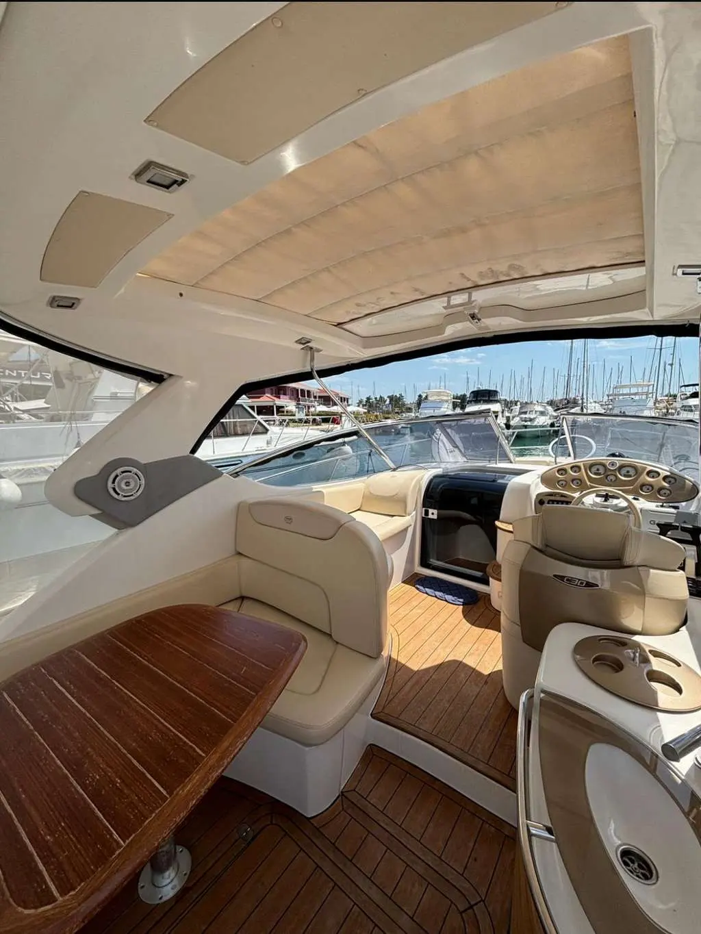 Sessa Marine C30 Hard-Top — Vue du cockpit avec table, sièges, poste de pilotage et marina en arrière-plan.