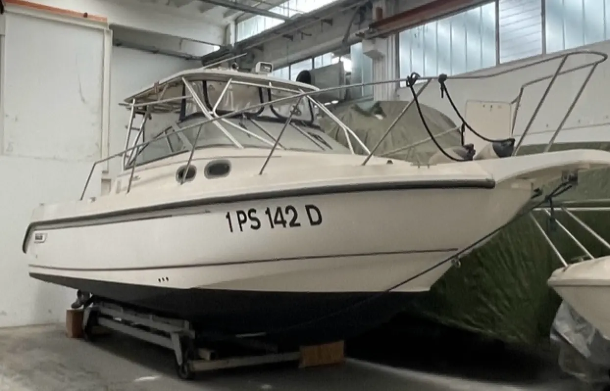 Boston Whaler 28 Conquest — Bateau blanc vu de trois quarts à terre dans un hangar, sur sa remorque.