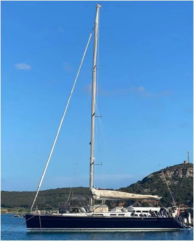 Grand Soleil 50 — Voilier bleu et blanc amarré, vu de profil, devant une côte rocheuse.